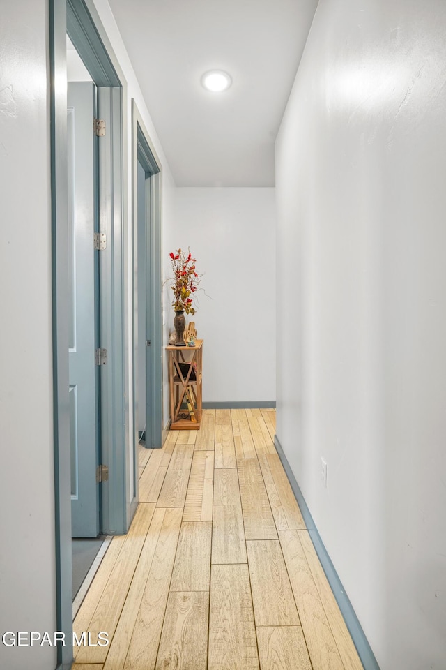 hallway featuring baseboards and wood finished floors