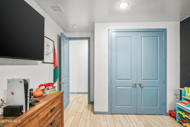 bedroom with wood finish floors, visible vents, baseboards, and a closet