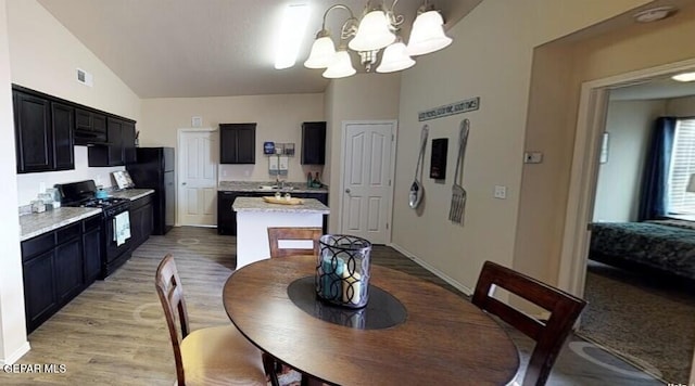 dining area featuring light wood-style floors, visible vents, lofted ceiling, and an inviting chandelier