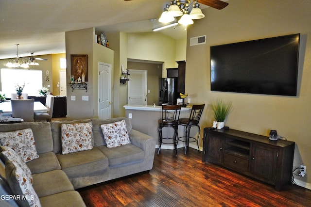 living room featuring visible vents, wood finished floors, vaulted ceiling, and ceiling fan with notable chandelier