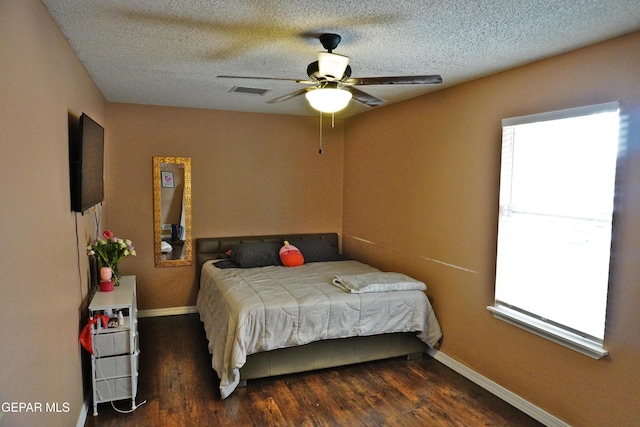 bedroom with visible vents, baseboards, wood finished floors, a textured ceiling, and a ceiling fan