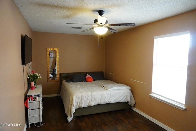 bedroom featuring a textured ceiling, baseboards, and wood finished floors