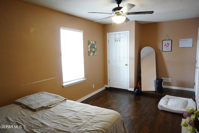 bedroom with visible vents, ceiling fan, baseboards, wood finished floors, and a textured ceiling