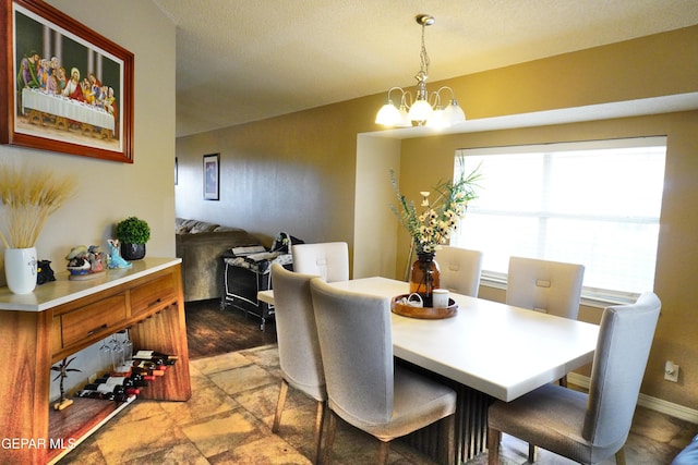 dining area featuring a notable chandelier, stone finish flooring, and baseboards