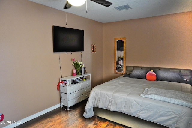 bedroom featuring ceiling fan, wood finished floors, visible vents, and baseboards