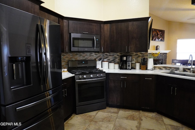 kitchen with a sink, stainless steel appliances, light countertops, dark brown cabinets, and backsplash