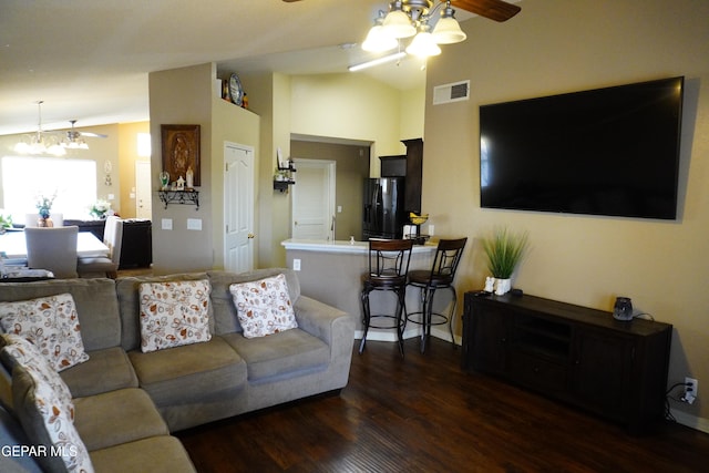 living area with dark wood finished floors, visible vents, ceiling fan with notable chandelier, and vaulted ceiling