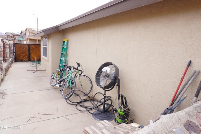 view of side of home with a gate, stucco siding, a patio, and fence