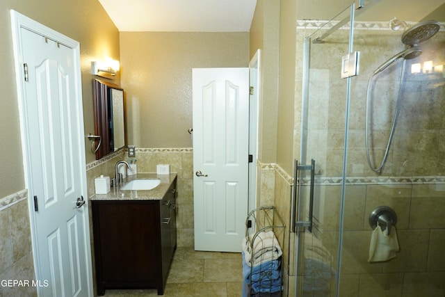 bathroom featuring tile walls, a stall shower, vanity, and tile patterned flooring