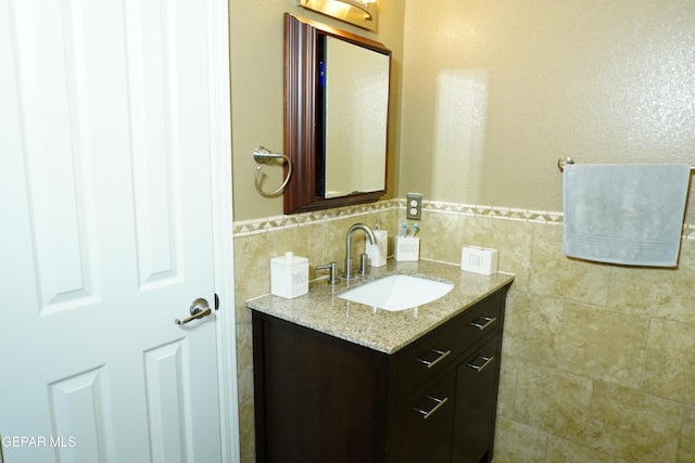 bathroom with a wainscoted wall, tile walls, and vanity