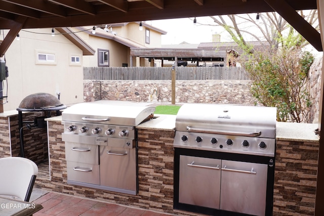 view of patio with grilling area, an outdoor kitchen, and fence