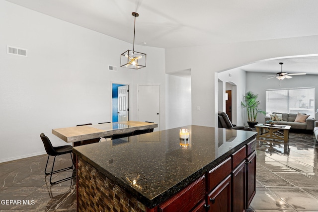 kitchen with visible vents, arched walkways, a center island, and a ceiling fan