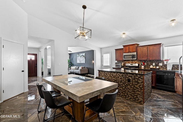 kitchen featuring dark countertops, a kitchen island, appliances with stainless steel finishes, arched walkways, and marble finish floor