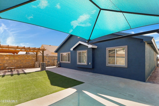 back of house with a yard, stucco siding, a pergola, and a patio