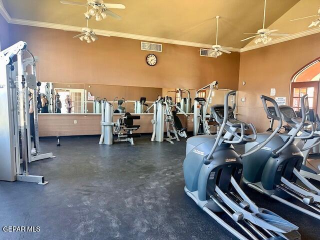 gym featuring a towering ceiling, visible vents, ceiling fan, and crown molding