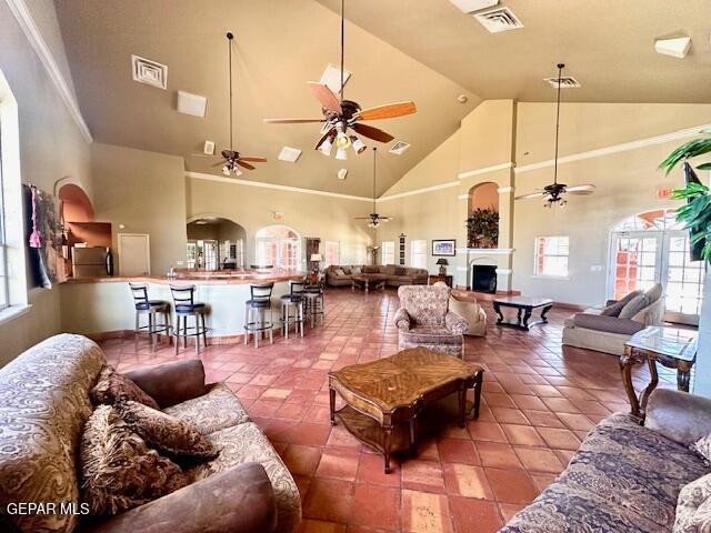 living room featuring tile patterned floors, visible vents, high vaulted ceiling, and ceiling fan