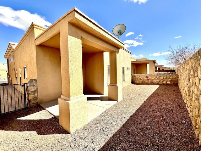 view of home's exterior with stucco siding and fence