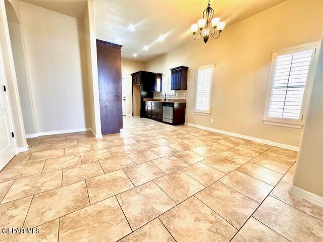 kitchen with baseboards, a chandelier, pendant lighting, light countertops, and stainless steel dishwasher