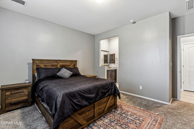 bedroom with visible vents, carpet flooring, ensuite bath, and baseboards