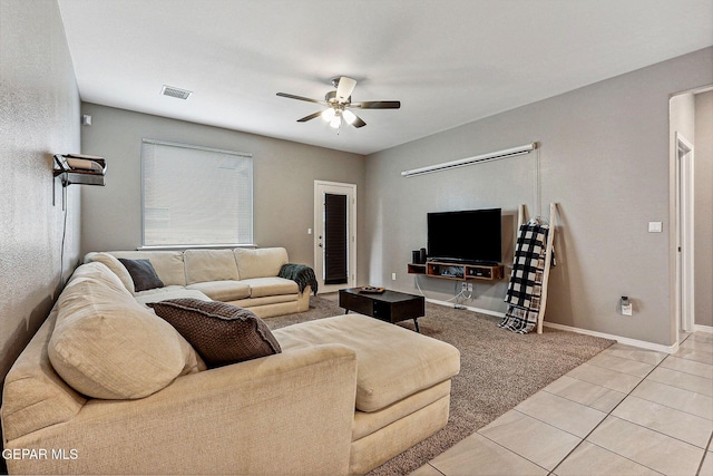 living room with light tile patterned floors, visible vents, baseboards, and a ceiling fan