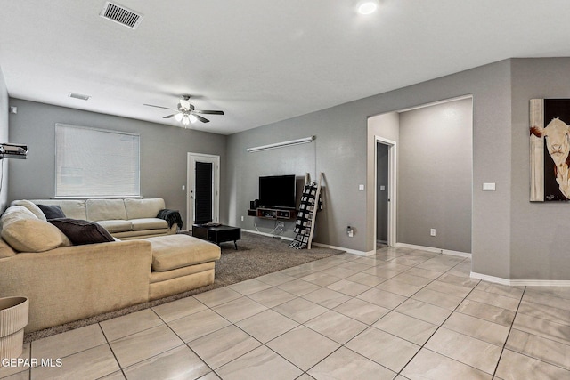 living area featuring light tile patterned floors, visible vents, baseboards, and ceiling fan