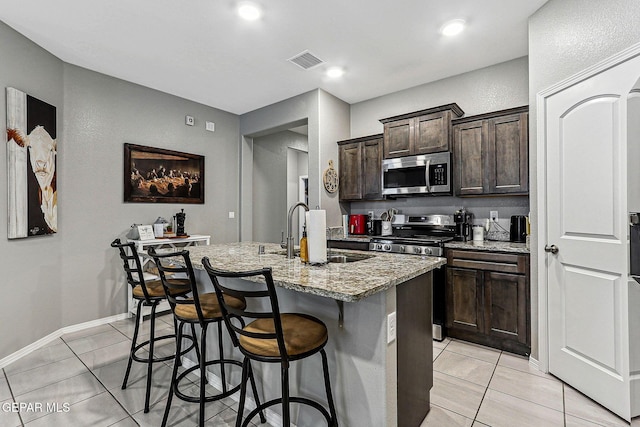 kitchen featuring visible vents, a center island with sink, a kitchen breakfast bar, stainless steel appliances, and a sink