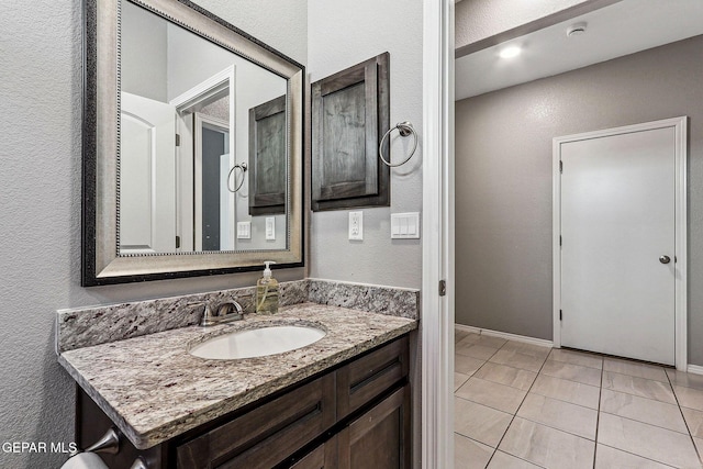 bathroom featuring vanity, a textured wall, and tile patterned flooring