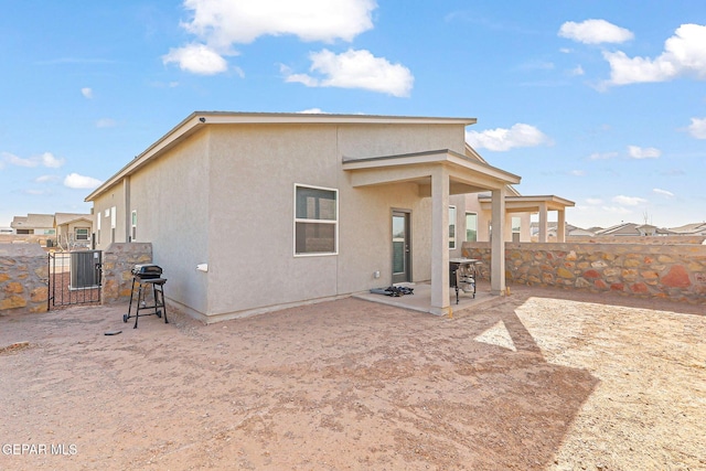 rear view of house with stucco siding, a patio, and fence