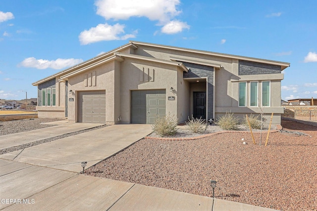 view of front of house featuring concrete driveway, an attached garage, fence, and stucco siding