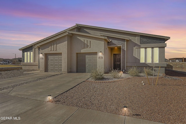 mid-century home featuring stucco siding, driveway, and a garage