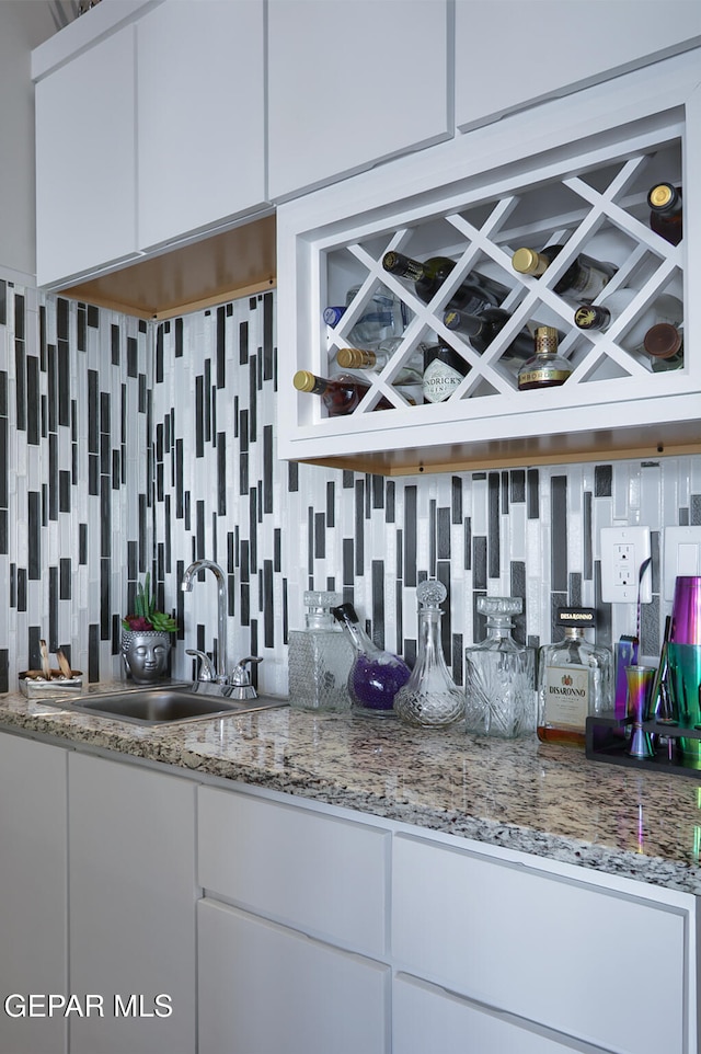 bar with decorative backsplash, a dry bar, and a sink