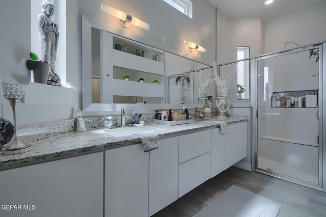 bathroom featuring a shower stall, double vanity, and a sink