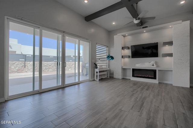 unfurnished living room featuring beamed ceiling, wood finished floors, a glass covered fireplace, recessed lighting, and ceiling fan