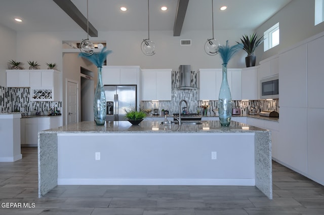 kitchen with beamed ceiling, wall chimney exhaust hood, visible vents, and built in microwave