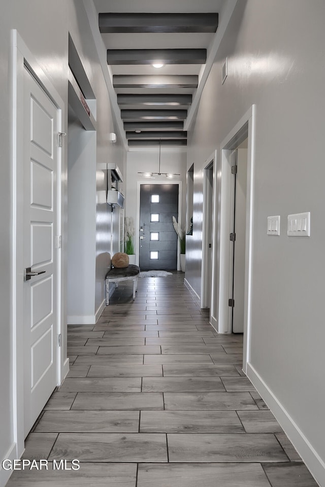 hall featuring baseboards, beam ceiling, and wood tiled floor