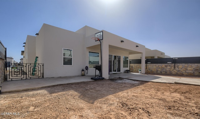 rear view of house featuring a patio, fence, and stucco siding