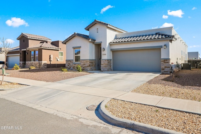 mediterranean / spanish house with stone siding, stucco siding, concrete driveway, and a garage