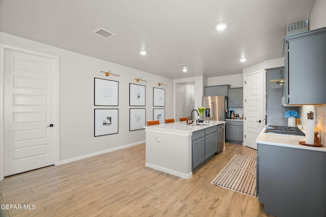 kitchen with visible vents, light wood finished floors, a sink, gray cabinetry, and light countertops