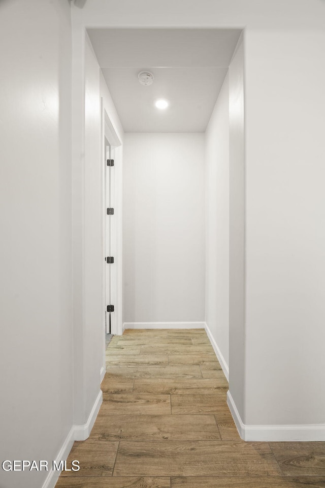 corridor featuring wood finished floors and baseboards