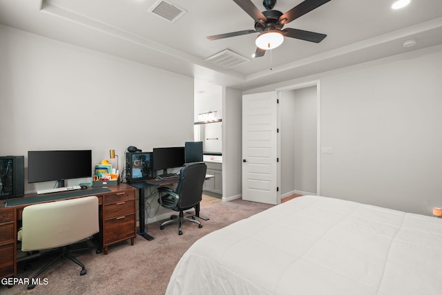 bedroom featuring visible vents, light carpet, a raised ceiling, and a ceiling fan