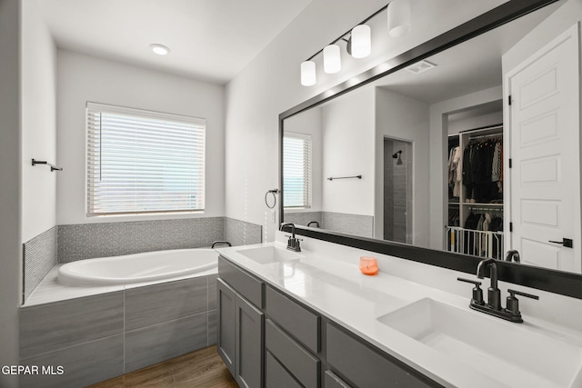 full bathroom with a sink, visible vents, a bath, and a spacious closet