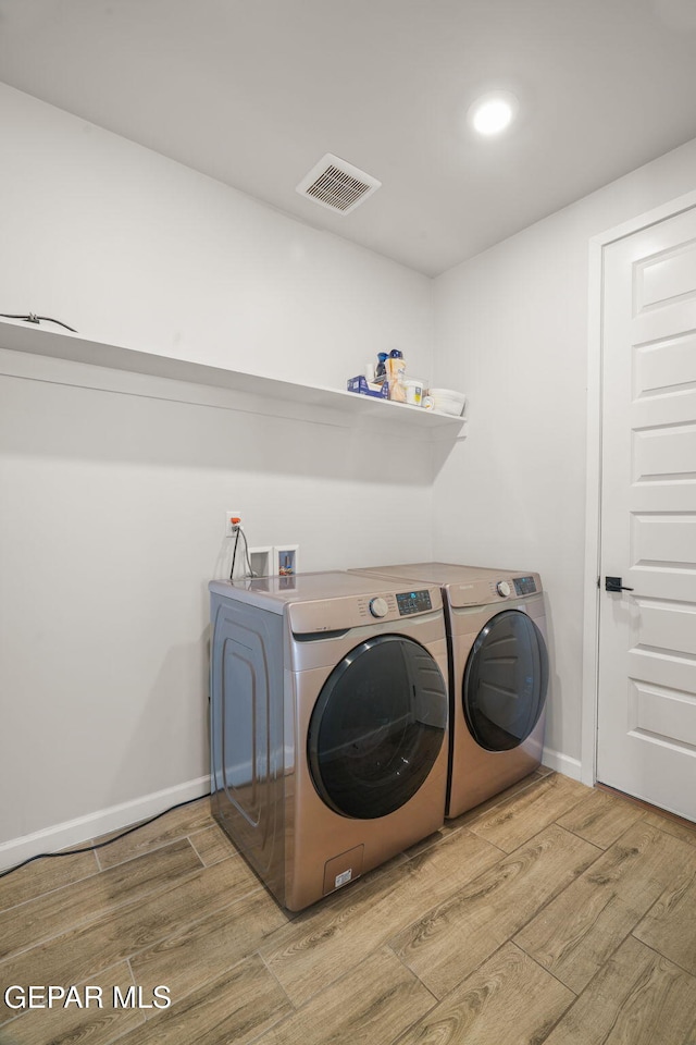 laundry room featuring washer and dryer, laundry area, wood finished floors, and visible vents