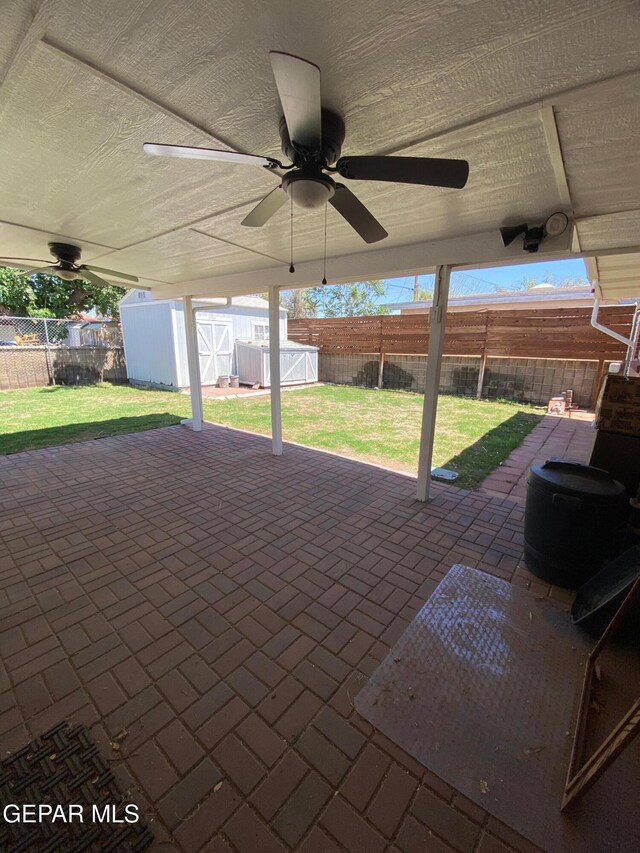 view of patio / terrace with an outdoor structure, a shed, a fenced backyard, and ceiling fan