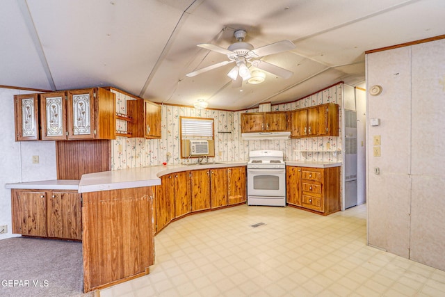 kitchen featuring brown cabinetry, light floors, a peninsula, under cabinet range hood, and white gas range