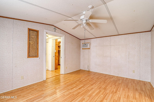 spare room featuring a wall mounted air conditioner, wood finished floors, crown molding, lofted ceiling, and ceiling fan