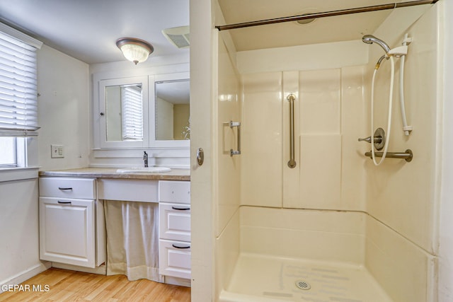 full bathroom featuring vanity, a shower stall, and wood finished floors