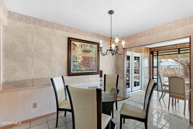 dining area with a textured wall, french doors, a chandelier, and tile patterned flooring