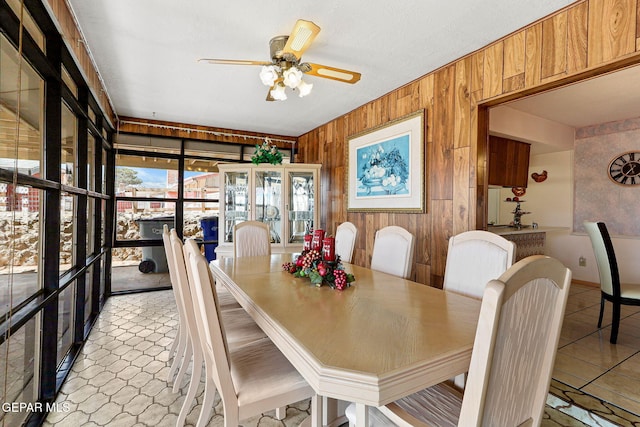 dining space with wooden walls and ceiling fan