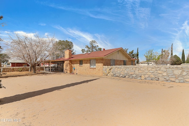 view of front of home with driveway, brick siding, and a chimney