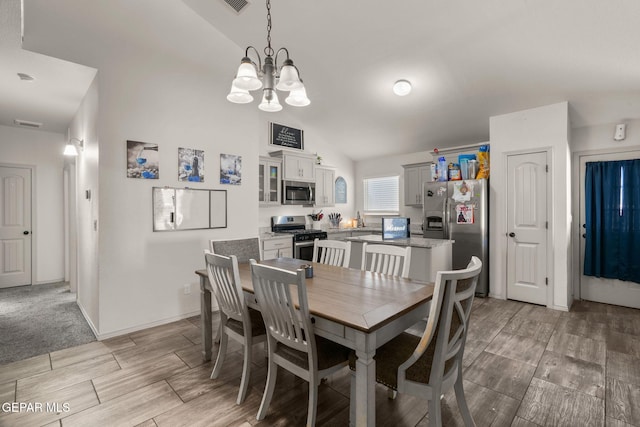 dining area with wood finish floors, baseboards, lofted ceiling, and a notable chandelier